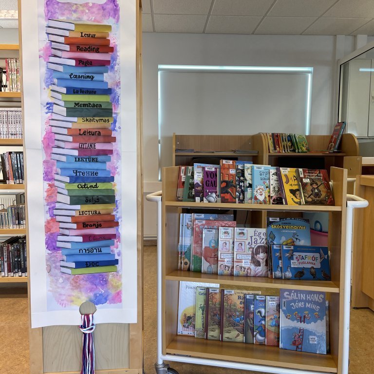 Veggspjald/listaverk eftir Konný Hrund myndmenntakennara, þar kemur fram orðið lestur á 18 tungumálum en það eru þau móðurmál sem nemendur skólans tala.